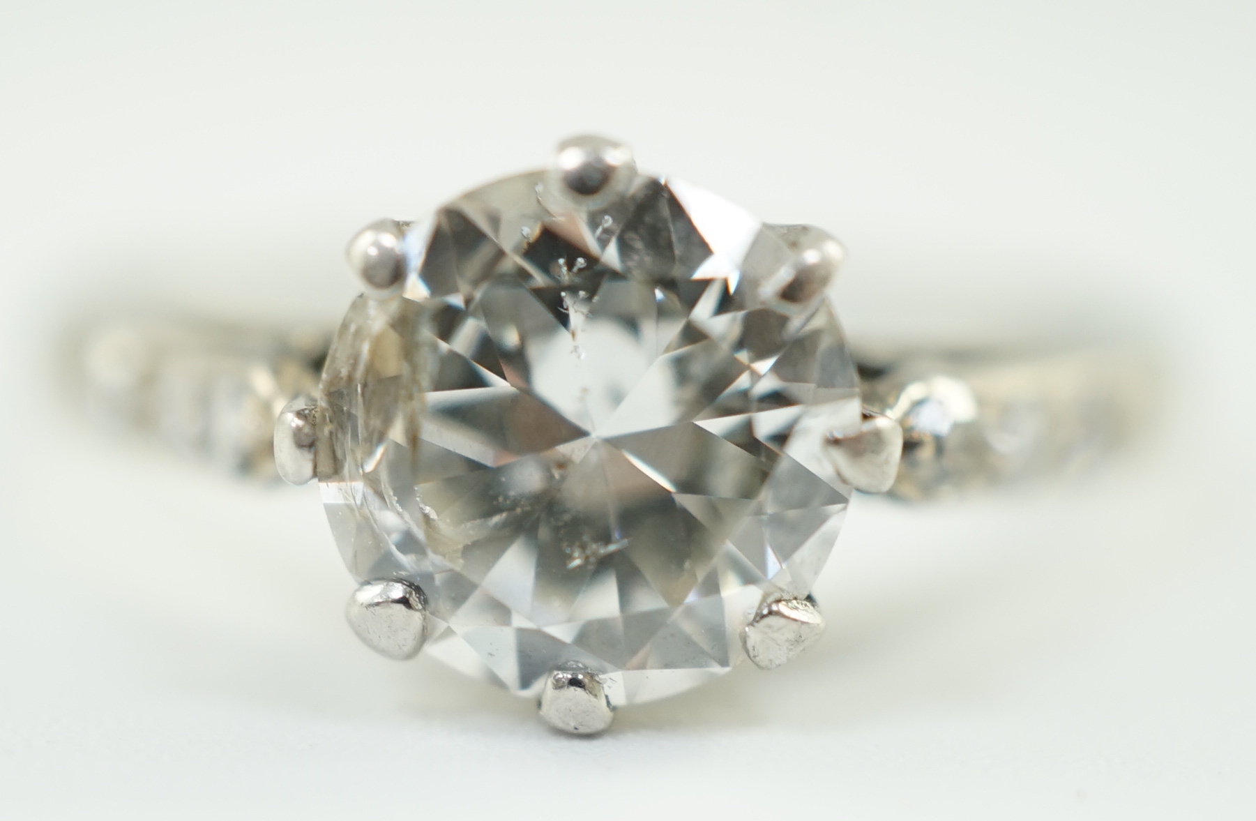 A platinum and single stone diamond ring, with diamond set shoulders